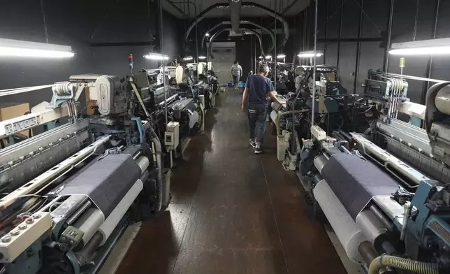 Weaver Shigeru Uchida and his colleague inspect vintage loom machines at Momotaro Jeans in Kojima, Okayama prefecture, western Japan, on Sept. 4, 2024. (AP Photo/Ayaka McGill)