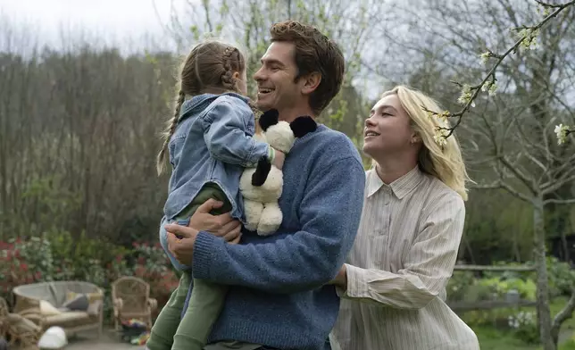 This image released by A24 shows Andrew Garfield, center, and Florence Pugh, right, in a scene from "We Live In Time." (Peter Mountain/A24 via AP)