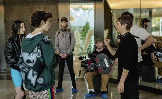 This image released by Neon shows Mikey Madison, left, and Mark Eydelshteyn, second left, with director Sean Baker, right, on the set of "Anora." (Augusta Quirk/Neon via AP)