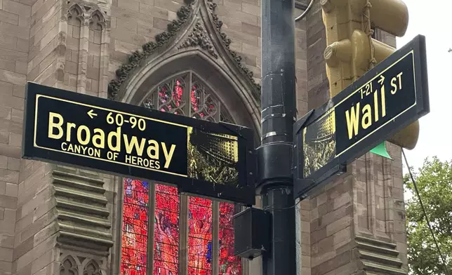 FILE - Signs mark the intersection of Broadway and Wall Street in the Financial District on Oct. 2, 2024, in New York. Trinity Church is in the background. (AP Photo/Peter Morgan, File)