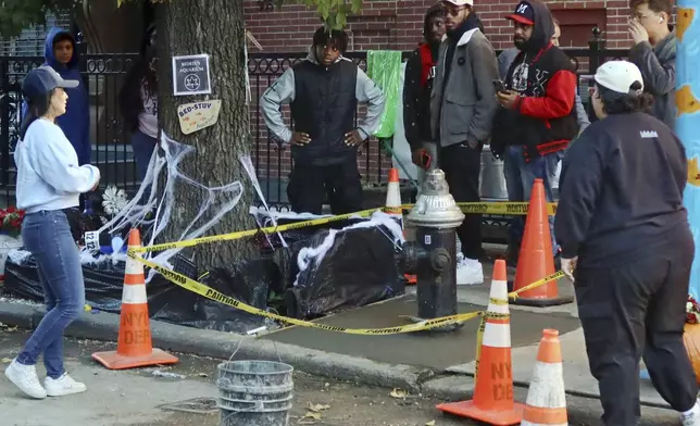 People gather at the yellow caution-taped area around a once leaky fire hydrant that became a makeshift aquarium goldfish pool, and now has been filled with concrete by the city, Friday, Oct. 25, 2024, in the Brooklyn borough of New York. (AP Photo/Cedar Attanasio)