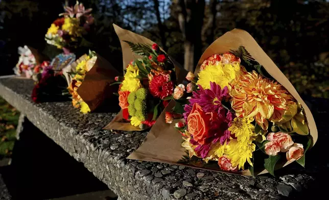 FILE- Bouquets of flowers line a stone picnic table at a roadside park as a small memorial to the victims of a mass shooting the day before in Fall City, Wash., Tuesday, Oct. 22, 2024. (Jennifer Buchanan/The Seattle Times via AP, File)