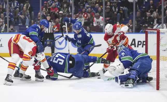 Vancouver Canucks goalie Arturs Silovs (31) stops Calgary Flames' Andrei Kuzmenko (96) as Vancouver's Aatu Raty (54), Tyler Myers (57) defend while Carson Soucy (7) ties up Calgary's Samuel Honzek (29) during the first period of an NHL hockey game, Wednesday, Oct. 9, 2024 in Vancouver, British Columbia. (Darryl Dyck/Canadian Press via AP)