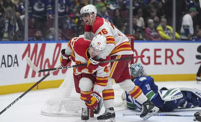 Calgary Flames' Connor Zary (47) and Martin Pospisil (76) celebrate Zary's winning goal against Vancouver Canucks goalie Arturs Silovs, back right, during overtime of an NHL hockey game in Vancouver, British Columbia, Wednesday, Oct. 9, 2024. (Darryl Dyck/The Canadian Press via AP)