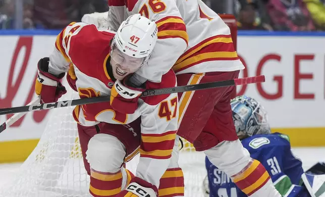 Calgary Flames' Connor Zary (47) and Martin Pospisil (76) celebrate Zary's winning goal against Vancouver Canucks goalie Arturs Silovs, back right, during overtime in an NHL hockey game in Vancouver, British Columbia, Wednesday, Oct. 9, 2024. (Darryl Dyck/The Canadian Press via AP)