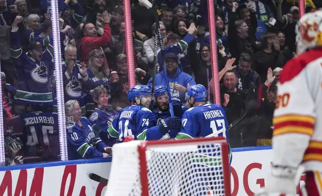 Vancouver Canucks' J.T. Miller, back center, Jake DeBrusk, left, and Filip Hronek celebrate Miller's goal against the Calgary Flames during the third period of an NHL hockey game in Vancouver, British Columbia, Wednesday, Oct. 9, 2024. (Darryl Dyck/The Canadian Press via AP)