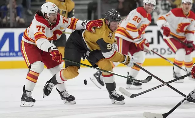 Vegas Golden Knights center Jack Eichel (9) and Calgary Flames left wing Ryan Lomberg (70) vie for the puck during the second period of an NHL hockey game Monday, Oct. 28, 2024, in Las Vegas. (AP Photo/John Locher)