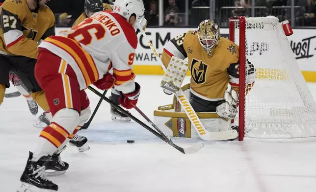 Calgary Flames left wing Andrei Kuzmenko (96) attempts a shot on Vegas Golden Knights goaltender Adin Hill (33) during the first period of an NHL hockey game Monday, Oct. 28, 2024, in Las Vegas. (AP Photo/John Locher)