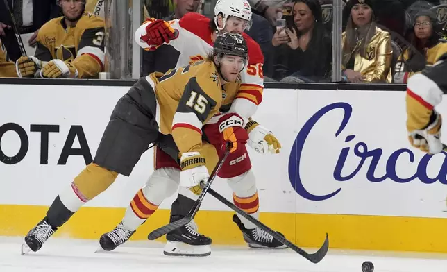 Vegas Golden Knights defenseman Noah Hanifin (15) and Calgary Flames center Justin Kirkland (58) vie for the puck during the first period of an NHL hockey game Monday, Oct. 28, 2024, in Las Vegas. (AP Photo/John Locher)