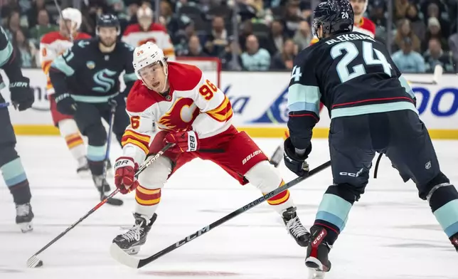 Calgary Flames forward Andrei Kuzmenko, left, skates against Seattle Kraken defenseman Jamie Oleksiak during the third period of an NHL hockey game, Saturday, Oct. 19, 2024, in Seattle. (AP Photo/Stephen Brashear)