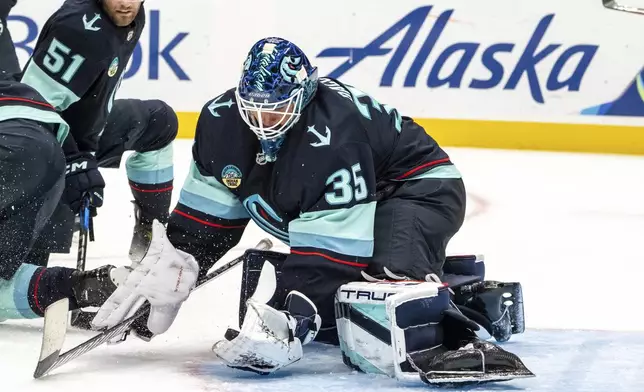 Seattle Kraken goalie Joey Daccord makes a glove save during the third period of an NHL hockey game against the Calgary Flames, Saturday, Oct. 19, 2024, in Seattle. (AP Photo/Stephen Brashear)