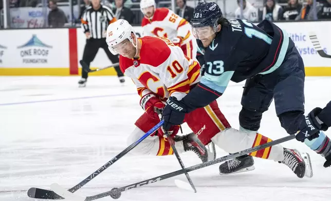 Calgary Flames forward Jonathan Huberdeau, left, and Seattle Kraken forward Brandon Tanev battle for the puck during the third period of an NHL hockey game, Saturday, Oct. 19, 2024, in Seattle. (AP Photo/Stephen Brashear)