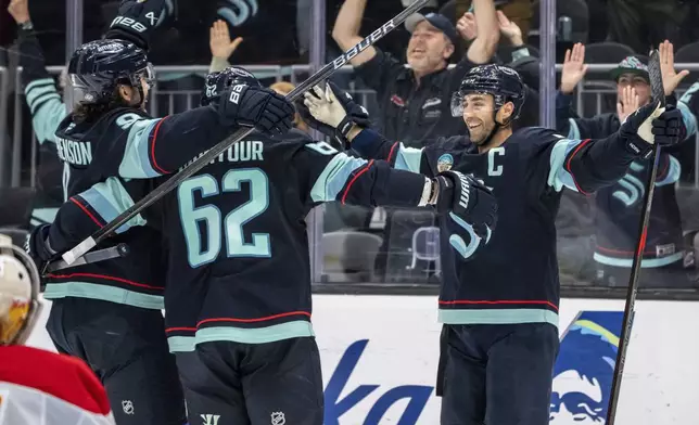 Seattle Kraken forward Jordan Eberle, right, celebrates with teammates, forward Chandler Stephenson, left, and defenseman Brandon Montour after scoring a goal during overtime of an NHL hockey game against the Calgary Flames, Saturday, Oct. 19, 2024, in Seattle. (AP Photo/Stephen Brashear)