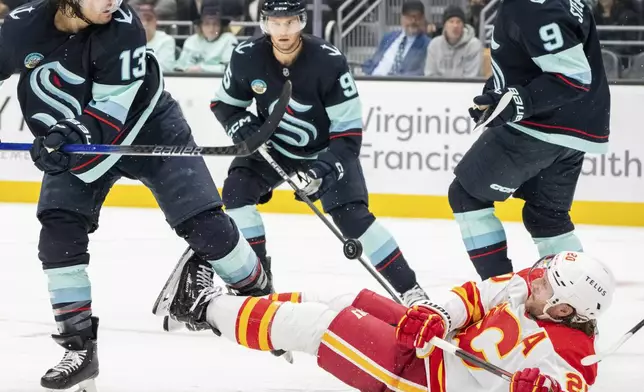 Calgary Flames forward Blake Coleman, on ice, battles Seattle Kraken forward Brandon Tanev, left, forward Chandler Stephenson, upper right, and forward Andre Burakovsky for the puck during the third period of an NHL hockey game, Saturday, Oct. 19, 2024, in Seattle. (AP Photo/Stephen Brashear)