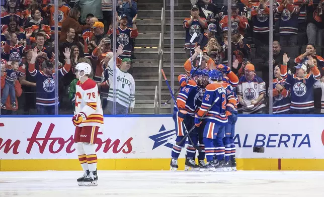 Calgary Flames' Martin Pospisil (76) skates past as Edmonton Oilers celebrate after a goal during first-period NHL hockey game action in Edmonton, Alberta, Sunday, Oct. 13, 2024. (Jason Franson/The Canadian Press via AP)