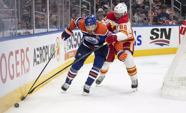 Calgary Flames' Daniil Miromanov (62) and Edmonton Oilers' Leon Draisaitl (29) battle for the puck during second period NHL action in Edmonton, Alberta, Sunday, Oct. 13, 2024. (Jason Franson/The Canadian Press via AP)