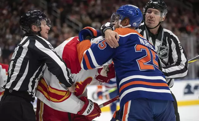 Calgary Flames' Kevin Bahl, second from left, and Edmonton Oilers' Darnell Nurse (25) rough it up during first-period NHL hockey game action in Edmonton, Alberta, Sunday, Oct. 13, 2024. (Jason Franson/The Canadian Press via AP)