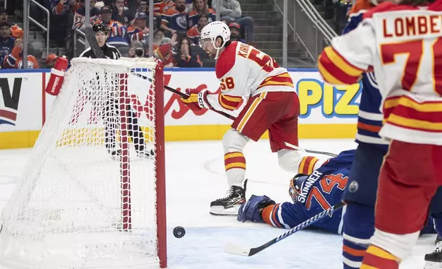 Calgary Flames' Justin Kirkland (58) scores on Edmonton Oilers' goalie Stuart Skinner (74) during third period NHL action in Edmonton, Sunday, Oct. 13, 2024. (Jason Franson/The Canadian Press via AP)