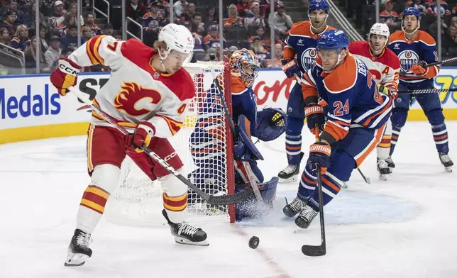 Calgary Flames' Connor Zary (47) and Edmonton Oilers' Travis Dermont (24) scramble for a rebound from Oilers goalie Stuart Skinner (74) during first-period NHL hockey game action in Edmonton, Alberta, Sunday, Oct. 13, 2024. (Jason Franson/The Canadian Press via AP)