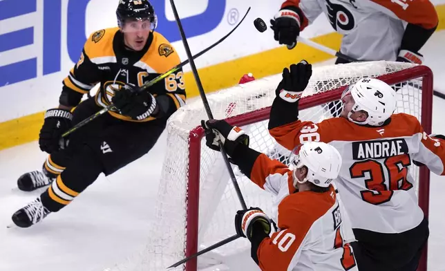 Philadelphia Flyers defenseman Emil Andrae (36) tries to grab the flying puck as Boston Bruins left wing Brad Marchand (63) gives chase during the second period of an NHL hockey game, Tuesday, Oct. 29, 2024, in Foxborough, Mass. (AP Photo/Charles Krupa)