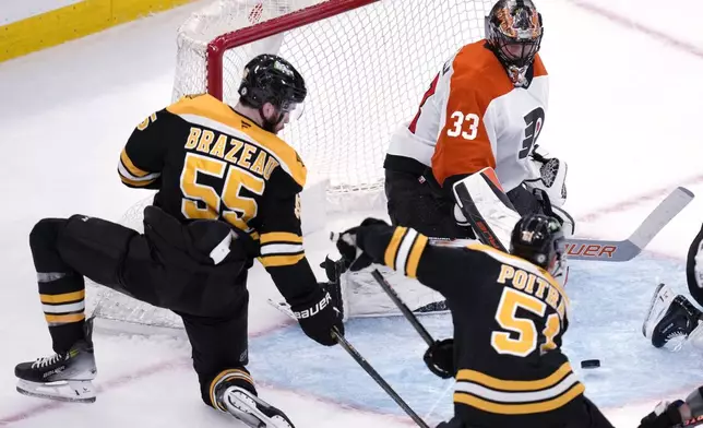 Philadelphia Flyers goaltender Samuel Ersson (33) watches the puck after making a save, before making a second save on a shot by Boston Bruins center Matthew Poitras (51) during the second period of an NHL hockey game, Tuesday, Oct. 29, 2024, in Foxborough, Mass. At left is Boston Bruins right wing Justin Brazeau (55). (AP Photo/Charles Krupa)