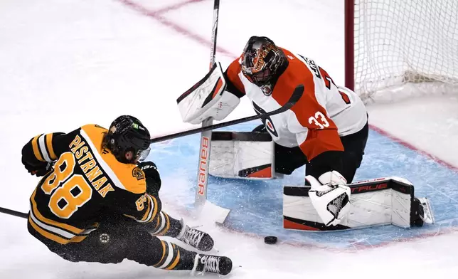 Philadelphia Flyers goaltender Samuel Ersson (33) drops to the ice to make a save on a shot by Boston Bruins right wing David Pastrnak (88) during the first period of an NHL hockey game, Tuesday, Oct. 29, 2024, in Foxborough, Mass. (AP Photo/Charles Krupa)