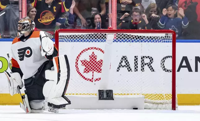 Philadelphia Flyers's goaltender Samuel Ersson kneels in his crease after Vancouver Canucks' Nils Hoglander scored during the first period of an NHL hockey game in Vancouver, British Columbia, Friday, Oct. 11, 2024. (Ethan Cairns/The Canadian Press via AP)