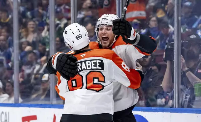 Philadelphia Flyers' Tyson Foerster, right, celebrates after his goal against the Vancouver Canucks with teammate Joel Farabee (86) during the first period of an NHL hockey game in Vancouver, British Columbia, Friday, Oct. 11, 2024. (Ethan Cairns/The Canadian Press via AP)