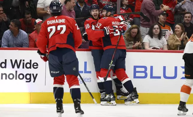 Washington Capitals right wing Taylor Raddysh (16) celebrates his goal with defenseman Dylan McIlrath (52) and right wing Brandon Duhaime (22) during the first period of an NHL hockey game against the Philadelphia Flyers, Wednesday, Oct. 23, 2024, in Washington. (AP Photo/Nick Wass)