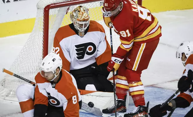 Philadelphia Flyers' goalie Ivan Fedotov, center left, blocks the net on Calgary Flames' Nazem Kadri (91) during the first period of an NHL hockey game in Calgary, Alberta, Saturday, Oct. 12, 2024. (Jeff McIntosh/The Canadian Press via AP)