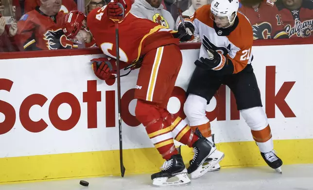 Philadelphia Flyers' Scott Laughton, right, checks Calgary Flames' Adam Klapka during the first period of an NHL hockey game in Calgary Alberta, Saturday, Oct. 12, 2024. (Jeff McIntosh/The Canadian Press via AP)