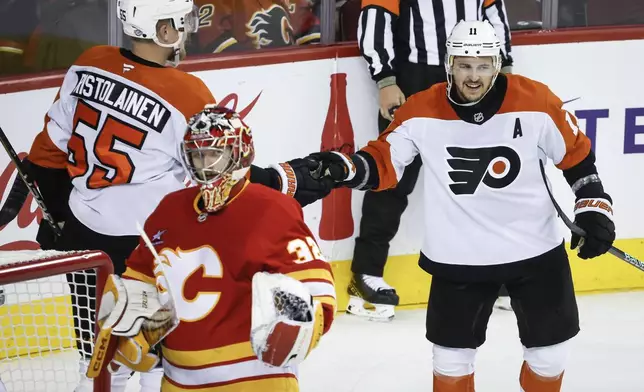 Philadelphia Flyers' Travis Konecny, right, celebrates his goal with teammate Rasmus Ristolainen (55) as Calgary Flames goalie Dustin Wolf looks away during the second period of an NHL hockey game in Calgary, Alberta, Saturday, Oct. 12, 2024. (Jeff McIntosh/The Canadian Press via AP)