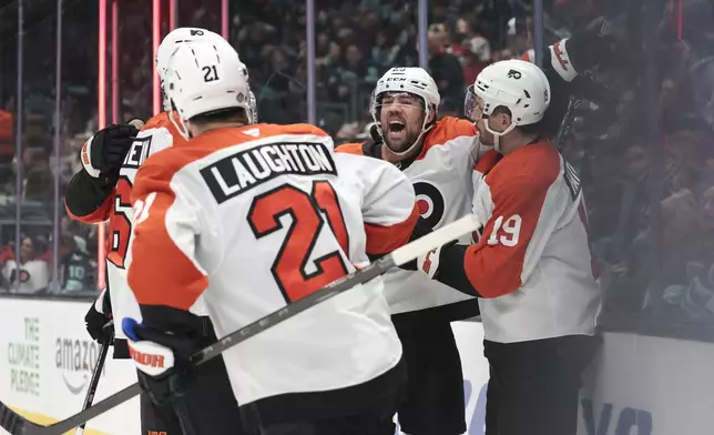 Philadelphia Flyers center Ryan Poehling, center, celebrates with Garnet Hathaway (19) and other teammates after center Scott Laughton (21) scored his second goal during the first period of an NHL hockey game against the Seattle Kraken, Thursday, Oct. 17, 2024, in Seattle. (AP Photo/Jason Redmond)