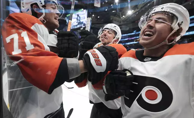 Philadelphia Flyers right wing Tyson Foerster (71), center Morgan Frost, center, and right wing Bobby Brink, right, come together along the glass as they warm up before an NHL hockey game against the Seattle Kraken Thursday, Oct. 17, 2024, in Seattle. (AP Photo/Jason Redmond)