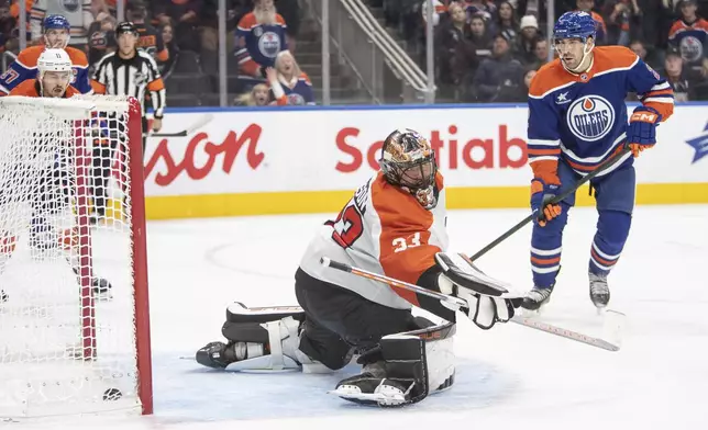 Philadelphia Flyers goalie Samuel Ersson (33) is scored on as Edmonton Oilers' Evan Bouchard (2) looks on during overtime of an NHL hockey game in Edmonton, Alberta, Tuesday, Oct. 15, 2024. (Amber Bracken/The Canadian Press via AP)