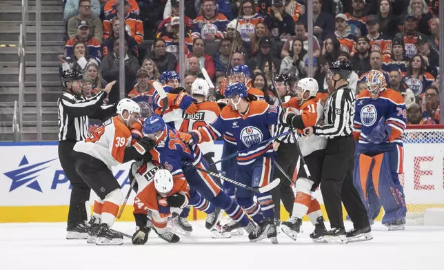 Philadelphia Flyers' Owen Tippett (74) and Edmonton Oilers' Darnell Nurse (25) mix it up as Flyers' Matvei Michkov (39) and Oilers' Derek Ryan (10) look on during the second period of an NHL hockey game in Edmonton, Alberta, Tuesday, Oct. 15, 2024. (Amber Bracken/The Canadian Press via AP)