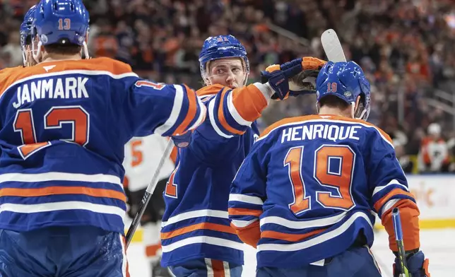 Edmonton Oilers' Mattias Janmark (13), Troy Stecher (51) and Adam Henrique (19) celebrate their goal against the Philadelphia Flyers during the second period of an NHL hockey game in Edmonton, Alberta, Tuesday, Oct. 15, 2024. (Amber Bracken/The Canadian Press via AP)