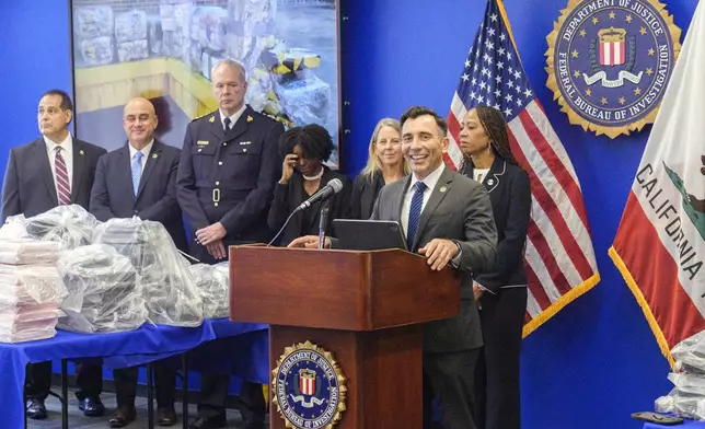 United States Attorney Martin Estrada, at podium, smiles as he's joined by federal, local, and international officials, to announce federal charges and arrests of alleged members of a transnational drug trafficking operation that routinely shipped hundreds of kilograms of cocaine from Colombia, through Mexico and Southern California, to Canada and other locations in the United States, during a news conference at the FBI offices in Los Angeles, Thursday, Oct. 17, 2024. (AP Photo/Damian Dovarganes)