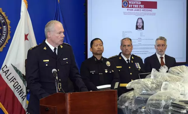 Chris Leather, chief superintendent with the Royal Canadian Mounted Police, at podium, joined by U.S.. federal, local, and international officials, announces federal charges and arrests of alleged members of a transnational drug trafficking operation that routinely shipped hundreds of kilograms of cocaine from Colombia, through Mexico and Southern California, to Canada and other locations in the United States, during a news conference at the FBI offices in Los Angeles, Thursday, Oct. 17, 2024. (AP Photo/Damian Dovarganes)