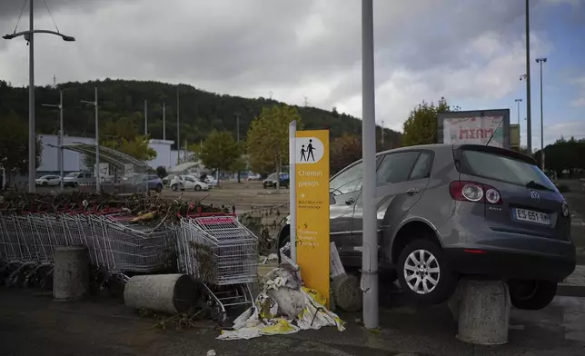 A car is seen in a parking lot of a shopping mall in Givors, central France, after torrential rains and flooding submerged roads and railways, Friday, Oct. 18, 2024. (AP Photo/Laurent Cirpiani)