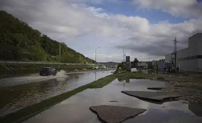 A car drives in a flooded street near a shopping mall in Givors, central France, after torrential rains and flooding submerged roads and railways, Friday, Oct. 18, 2024. (AP Photo/Laurent Cirpiani)