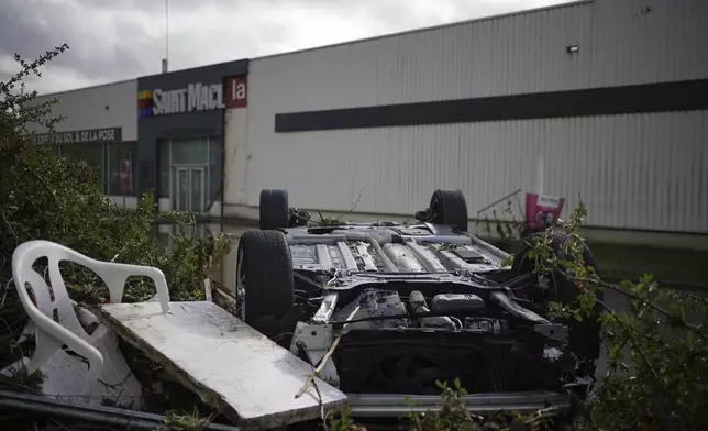 An overturned car is seen in a parking lot of a shopping mall in Givors, central France, after torrential rains and flooding submerged roads and railways, Friday, Oct. 18, 2024. (AP Photo/Laurent Cirpiani)