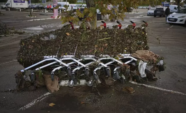 Shopping trolleys are seen in a parking lot of a shopping mall in Givors, central France, after torrential rains and flooding submerged roads and railways, Friday, Oct. 18, 2024. (AP Photo/Laurent Cirpiani)