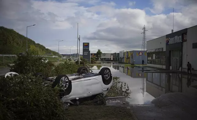 An overturned car is seen in a parking lot of a shopping mall in Givors, central France, after torrential rains and flooding submerged roads and railways, Friday, Oct. 18, 2024. (AP Photo/Laurent Cirpiani)