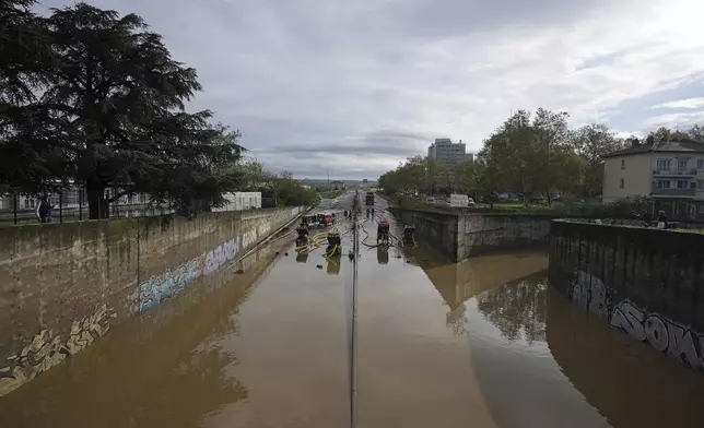 Firefighters pump out water in Givors, central France, after torrential rains and flooding submerged roads and railways, Friday, Oct. 18, 2024. (AP Photo/Laurent Cirpiani)