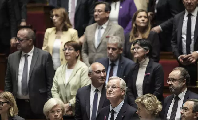 France's Prime Minister Michel Barnier, center, stands among lawmakers as he arrives at the National Assembly to deliver a speech, in Paris, Tuesday, Oct. 1, 2024. (AP Photo/Thibault Camus)