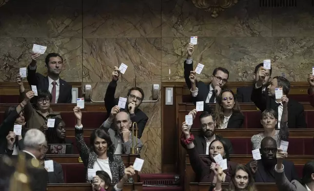 Members of the French unbowed party show their voting cards during the speech Prime Minister Michel Barnier arrives at the National Assembly, in Paris, Tuesday, Oct. 1, 2024. (AP Photo/Thibault Camus)