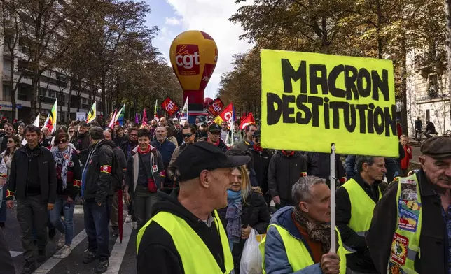 A protester holds a placard that reads, "Macron impeachment" during a rally against the new government of French Prime Minister Michel Barnier, in Paris, Tuesday, Oct. 1, 2024. (AP Photo/Louise Delmotte)