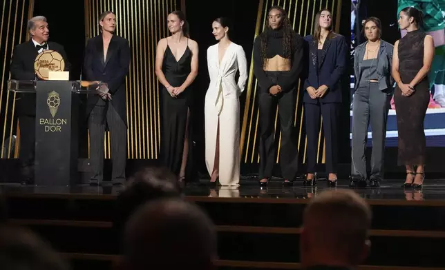 Barcelona's President Joan Laporta, left, and Spanish players from left, Alexia Putellas, Caroline Graham Hansen, Aitana Bonmati, Salma Paralluelo, Patri Guijarro, Mariona Caldentey, Marta Torrejon as they receive the Best Women's Club of the Year trophy during the 68th Ballon d'Or (Golden Ball) award ceremony at Theatre du Chatelet in Paris, Monday, Oct. 28, 2024. (AP Photo/Michel Euler)