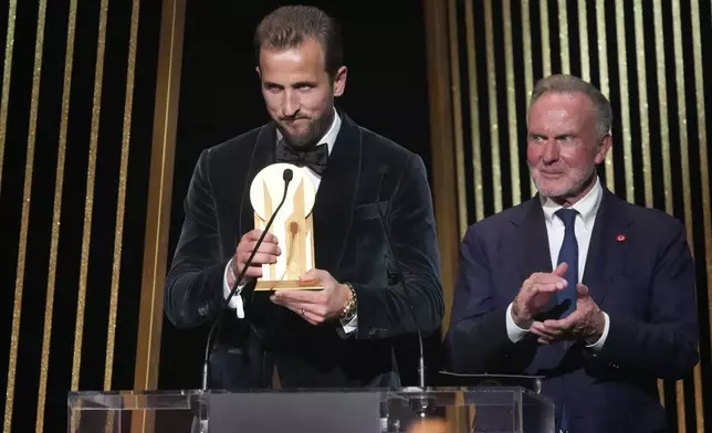 England's player Harry Kane, left, is flanked by former German player Karl-Heinz Rummenigge as he receives the Gerd Mueller trophy during the 68th Ballon d'Or (Golden Ball) award ceremony at Theatre du Chatelet in Paris, Monday, Oct. 28, 2024. (AP Photo/Michel Euler)